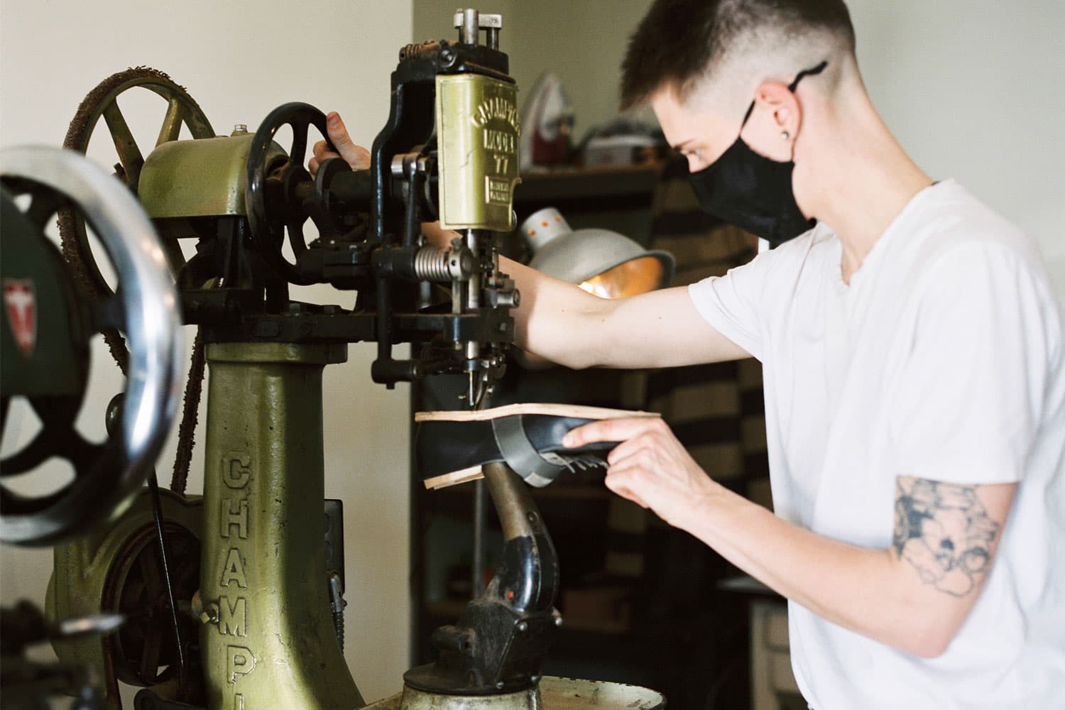 Ariss Grutter uses a large machine to resole a leather shoe in their East Vancouver workshop, Awl Together Leather.